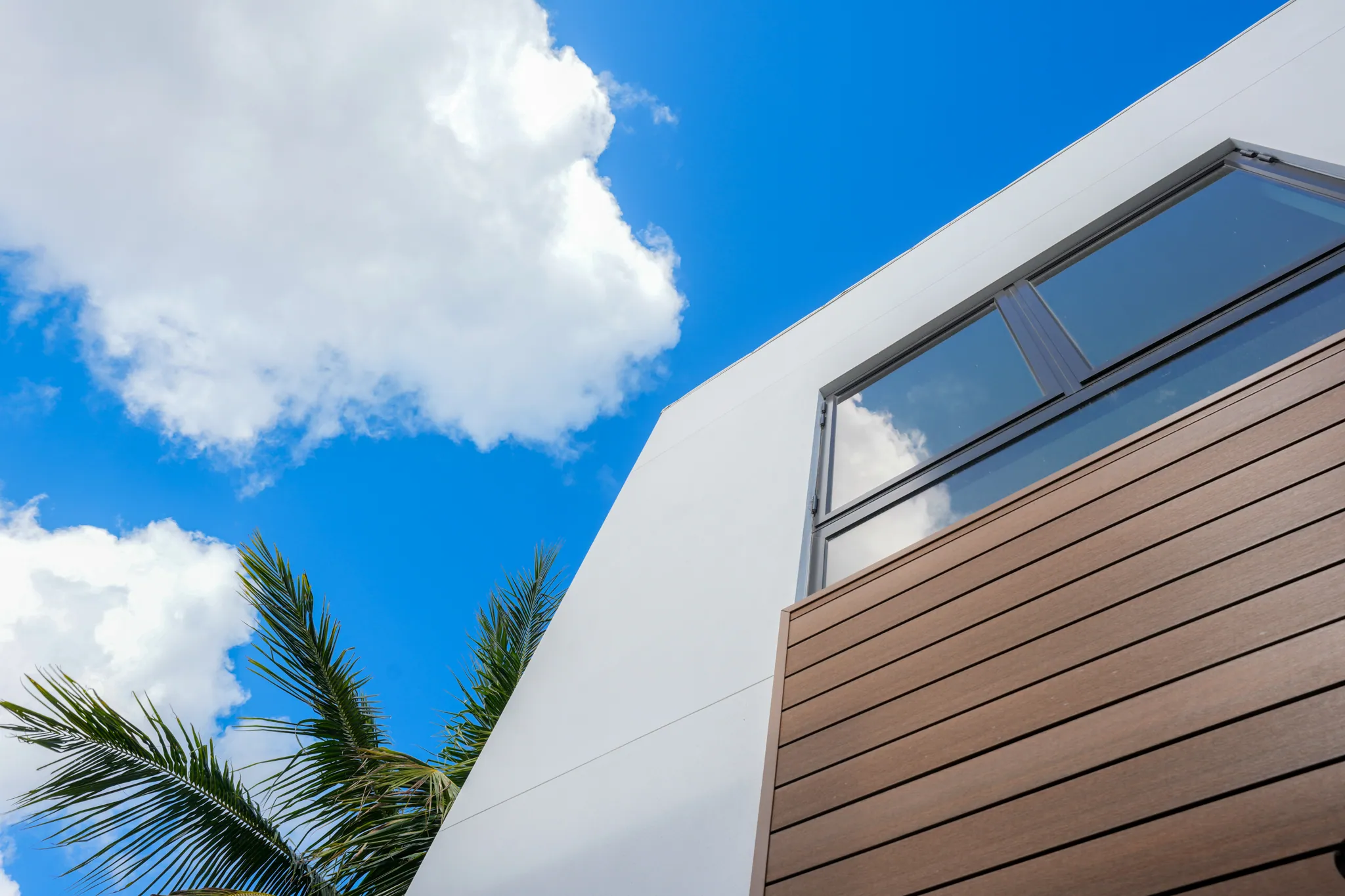Architectural detail of white facade meeting wood-paneled exterior wall with corner window