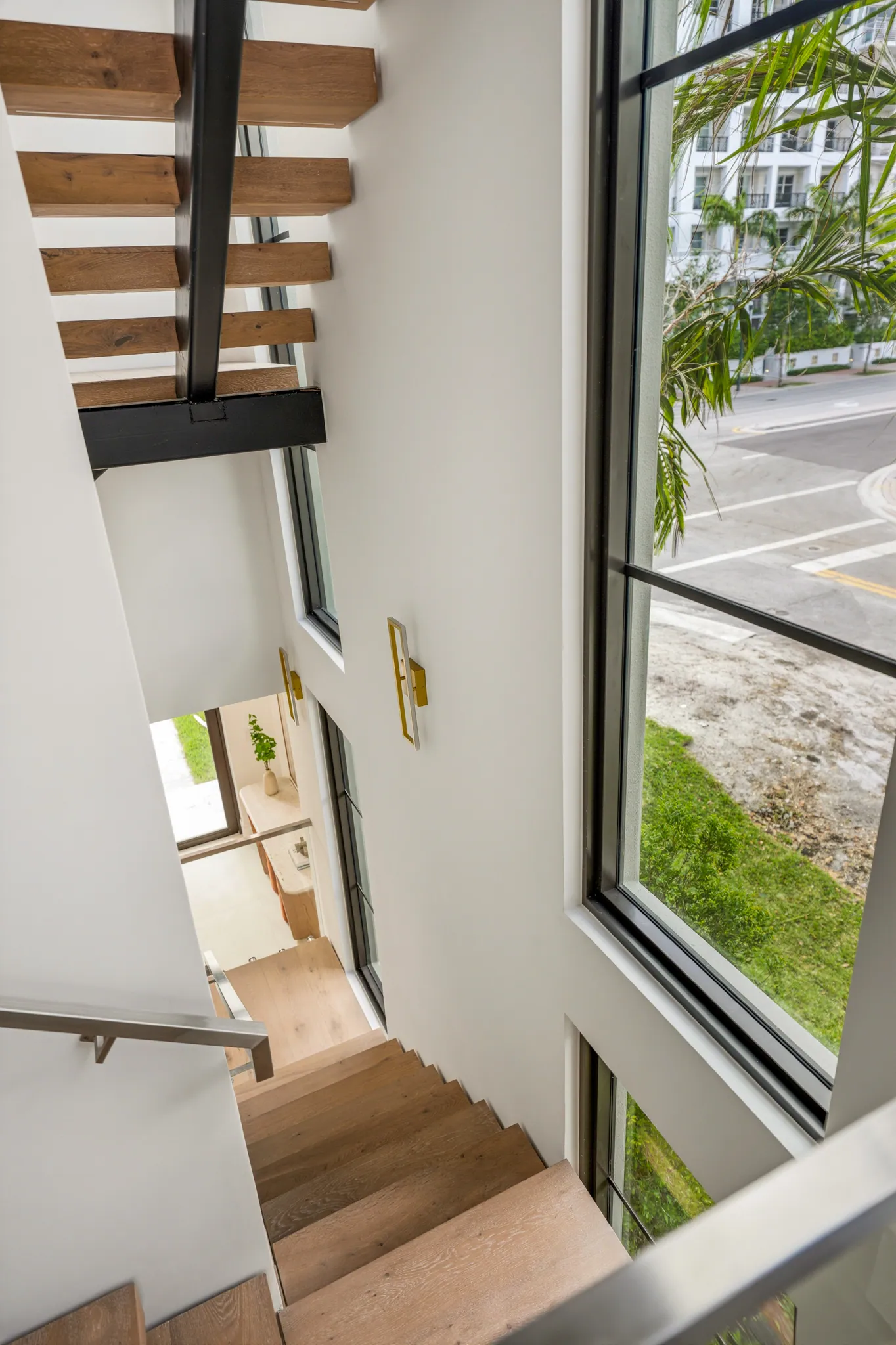 Stairwell view down toward entry with brass sconces and street outlook