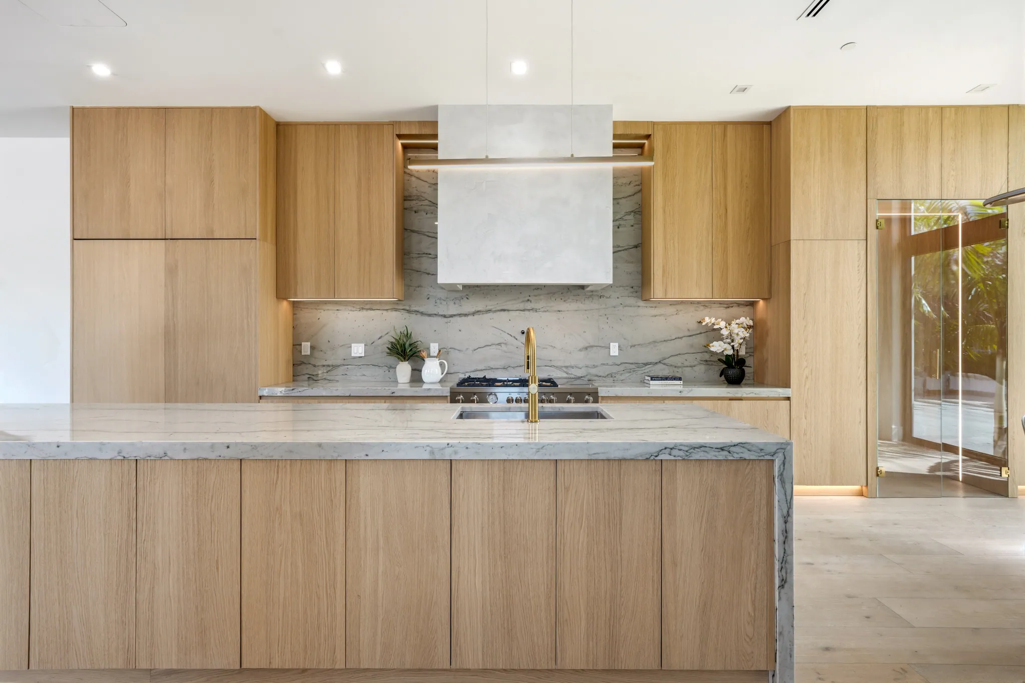 Kitchen with oak cabinetry, marble island, and integrated plaster range hood