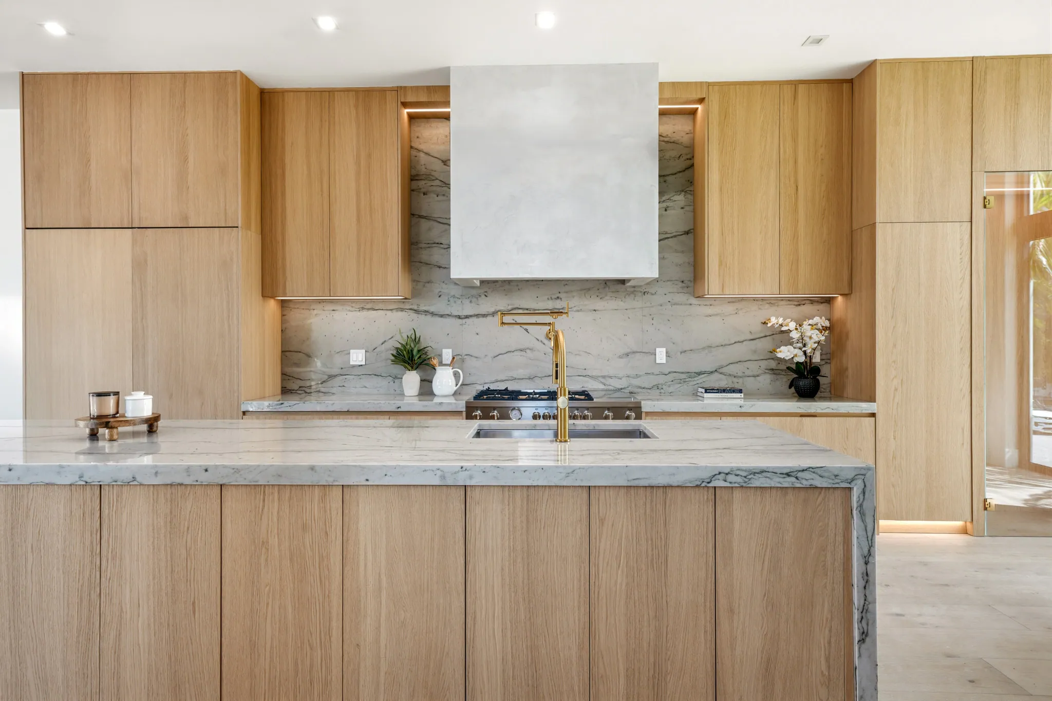 Kitchen island with quartzite waterfall, brass faucet, and oak cabinetry