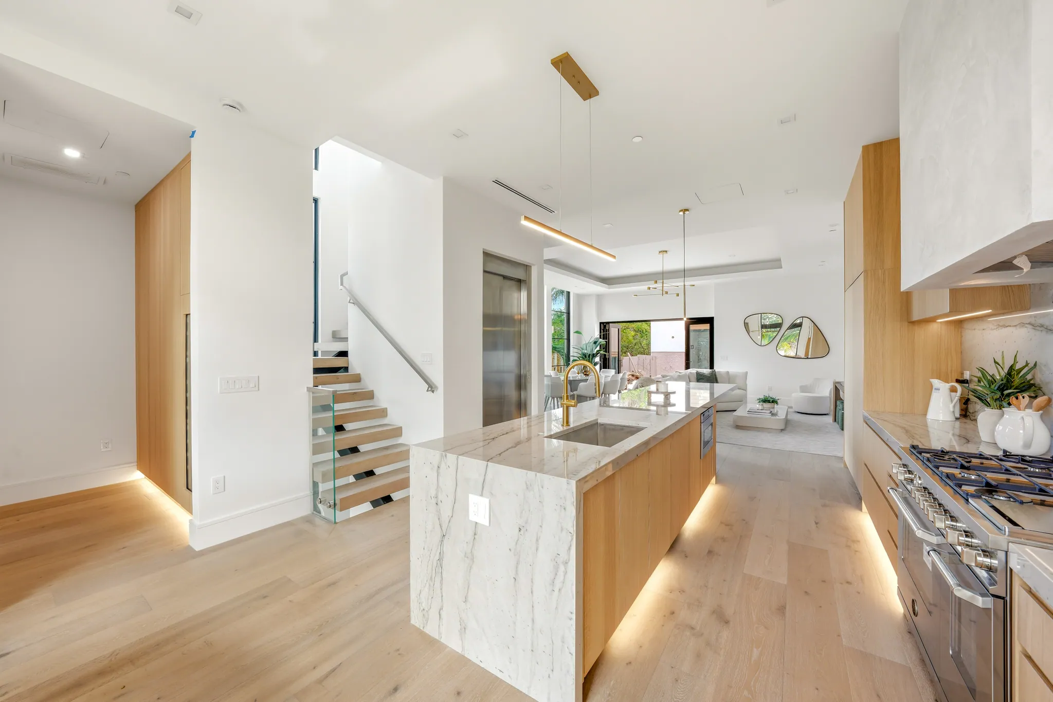 Open kitchen with marble waterfall island looking toward great room and terrace