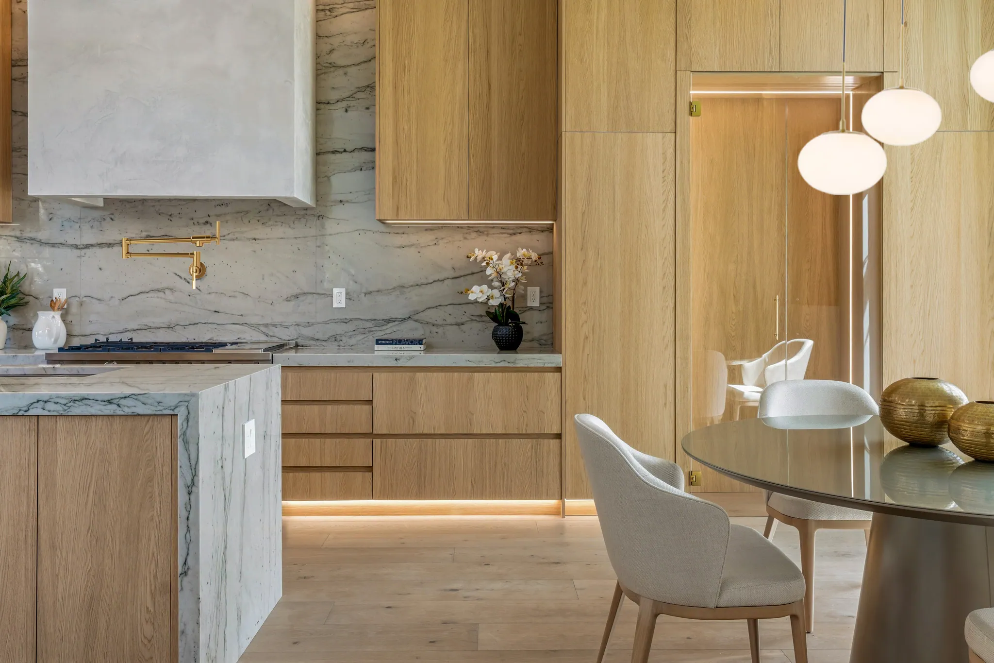Kitchen with quartzite backsplash, white oak cabinetry, and adjacent round dining table