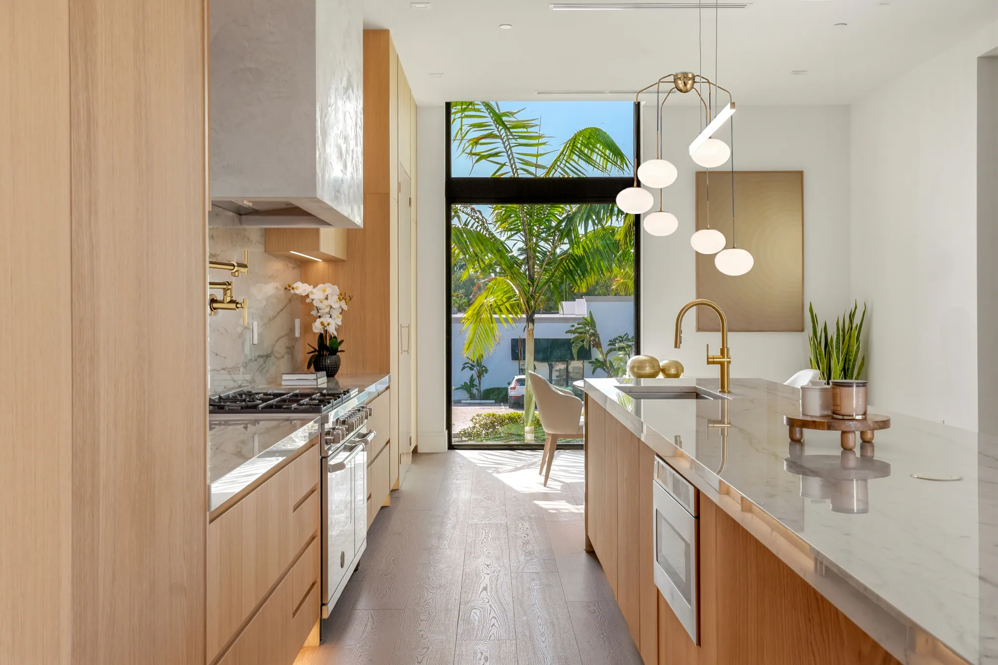Kitchen corridor opening to courtyard with pendant lights and waterfall island