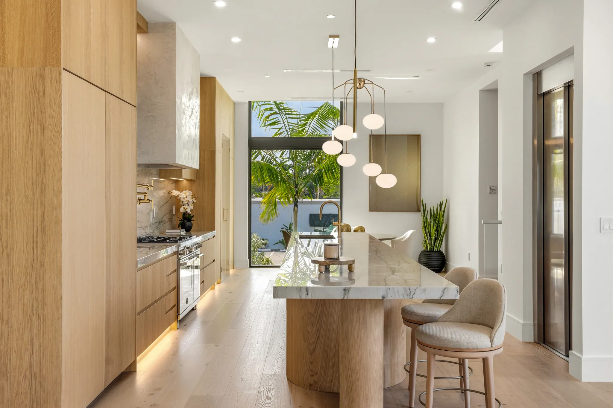 Kitchen island with marble counter, upholstered stools, and pendant cluster overhead