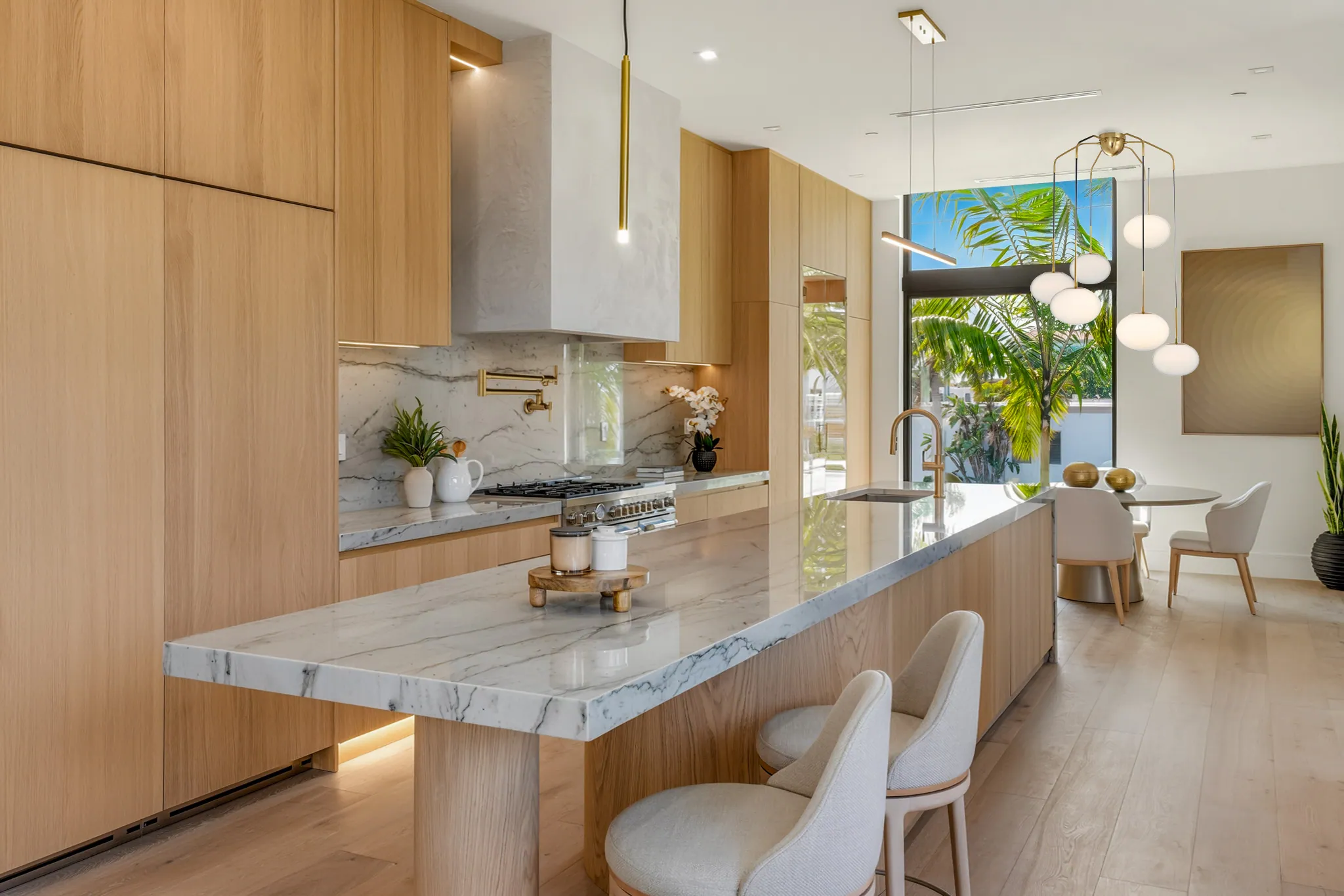 Kitchen with gas range, pot filler, marble waterfall island, and dining beyond