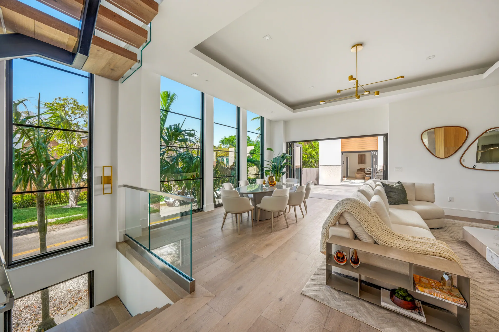 Open great room with floor-to-ceiling glass, dining table, and sectional sofa