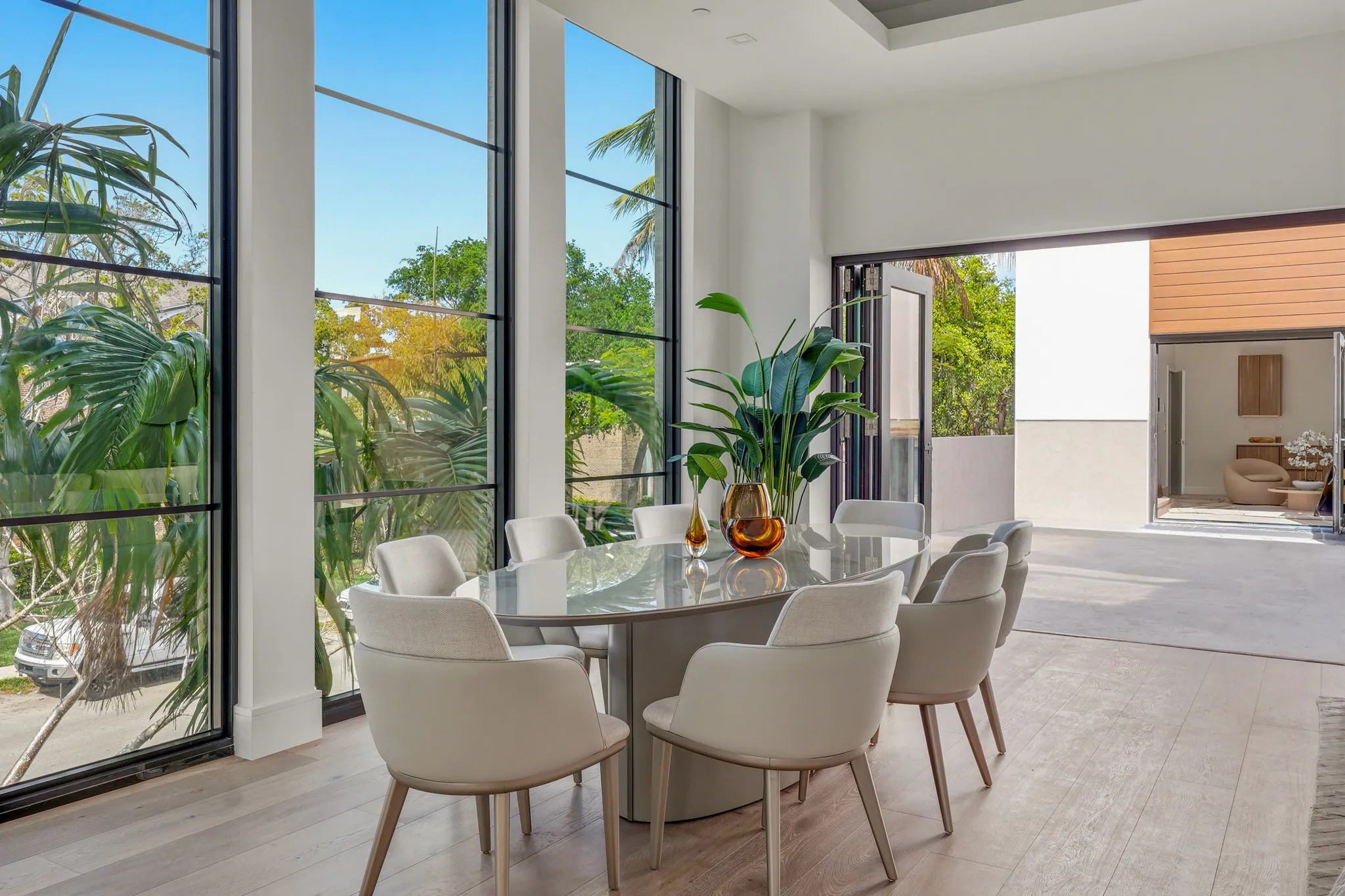 Dining area with oval table, eight chairs, and full-height steel-frame windows
