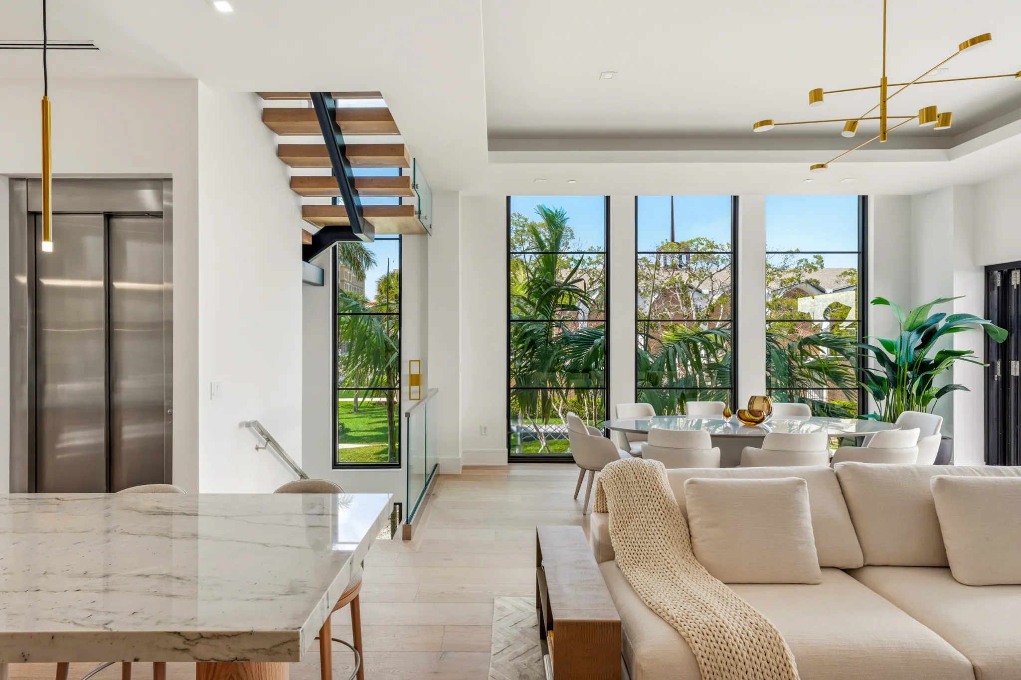 Great room view with elevator, floating staircase, and adjacent dining area