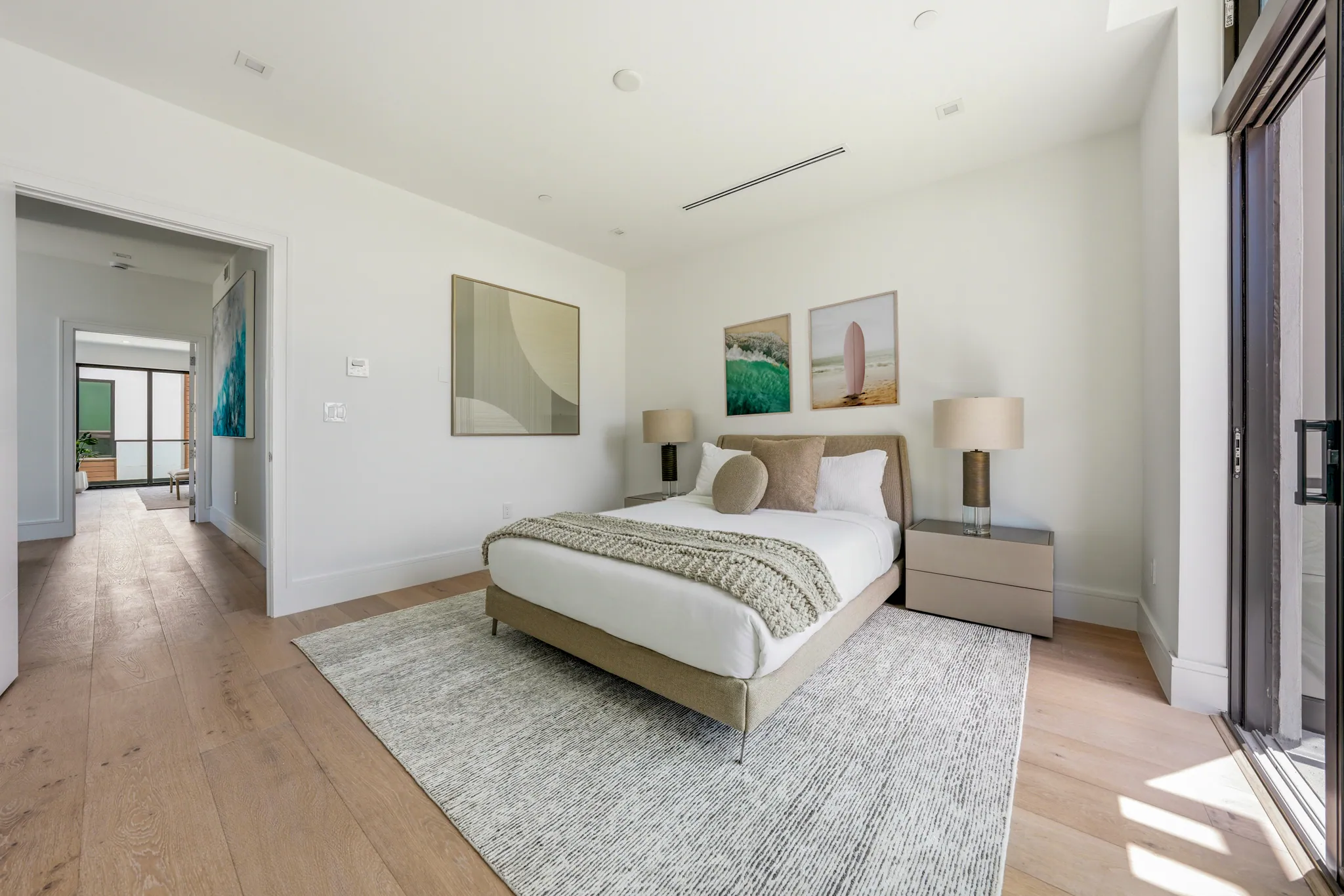 Secondary bedroom with upholstered bed, framed art, and white oak plank flooring