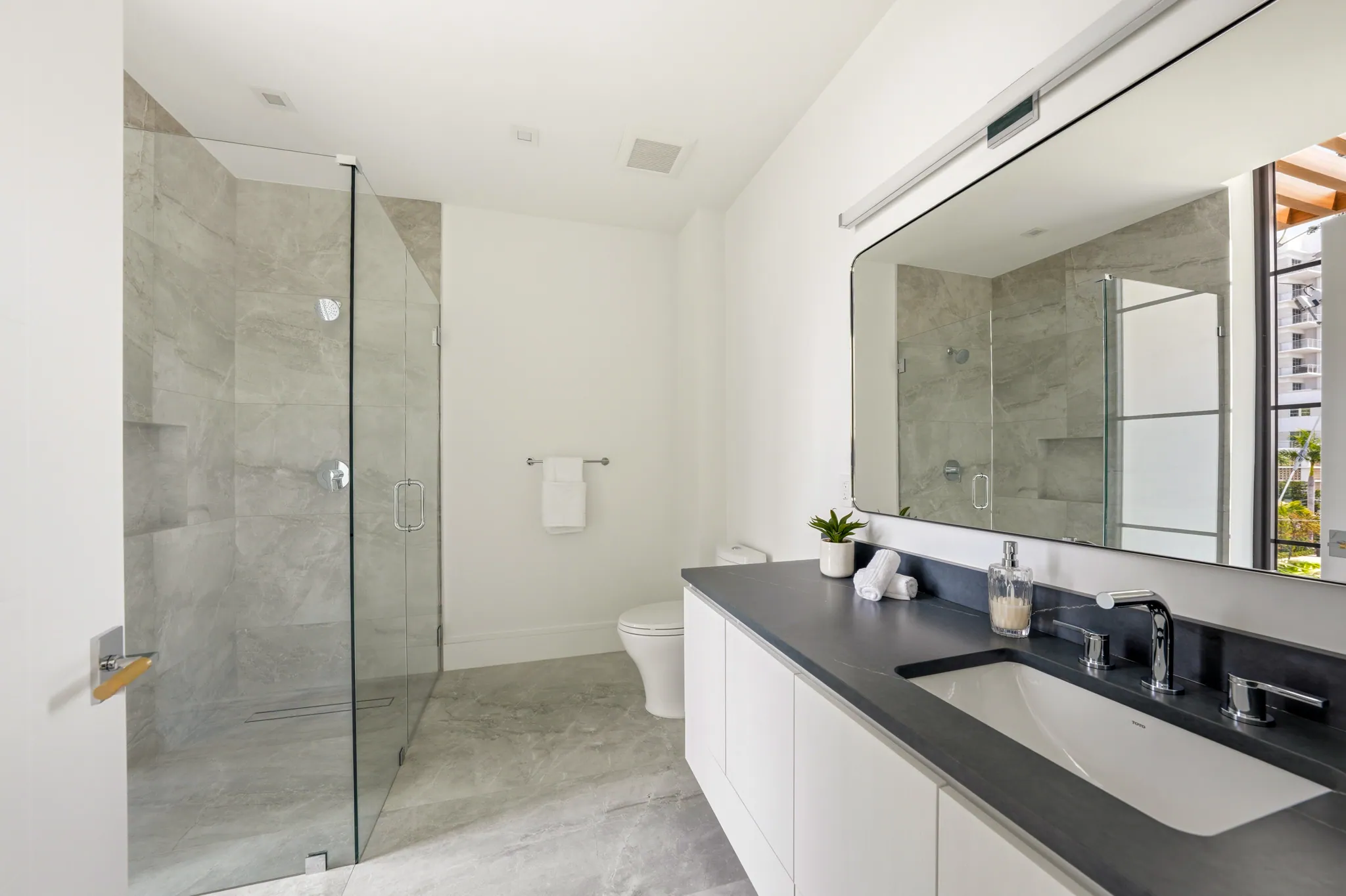 Secondary bath with walk-in shower, black quartzite vanity, and large framed mirror