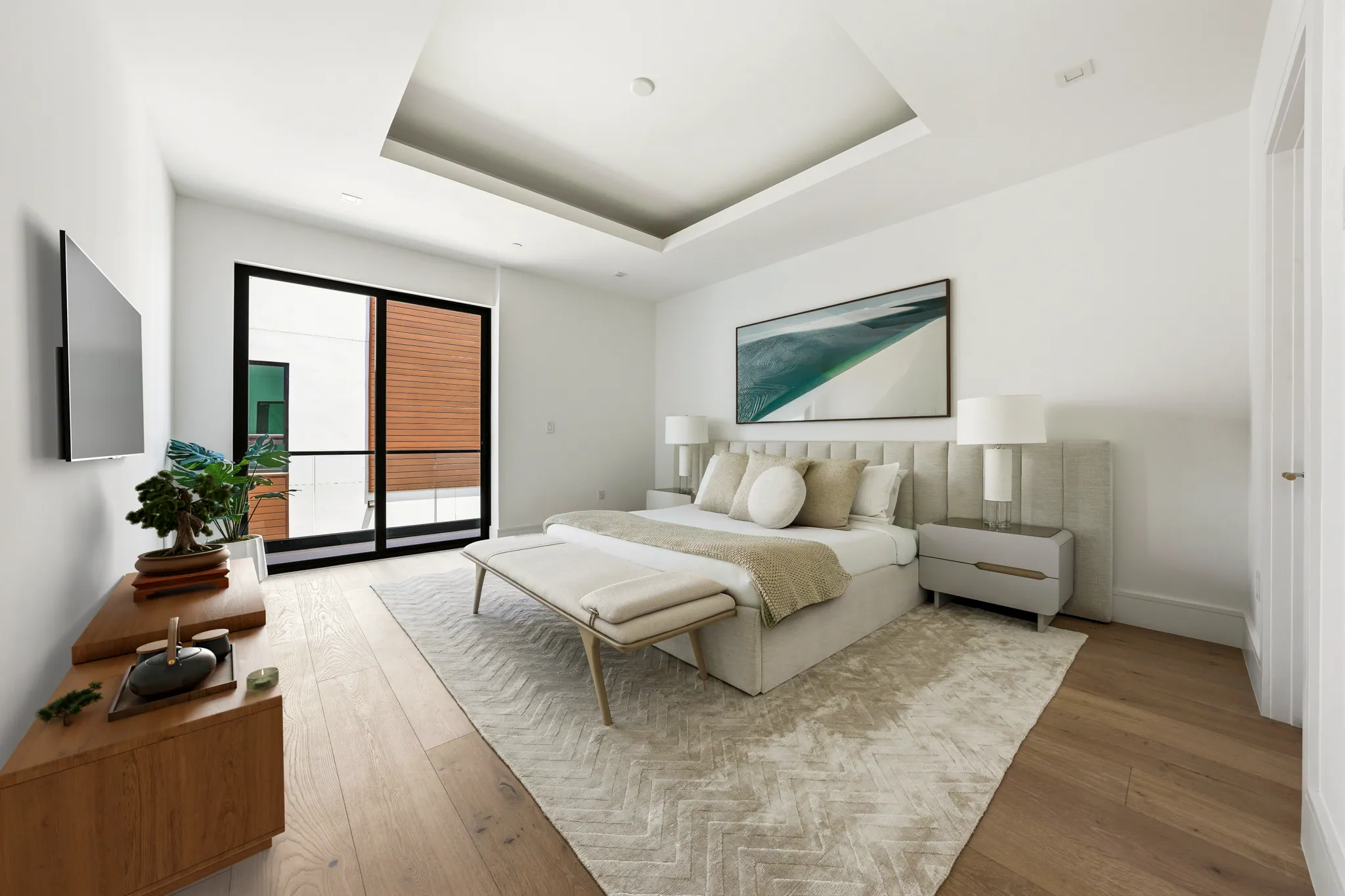 Primary bedroom with tray ceiling, upholstered headboard, and private terrace access