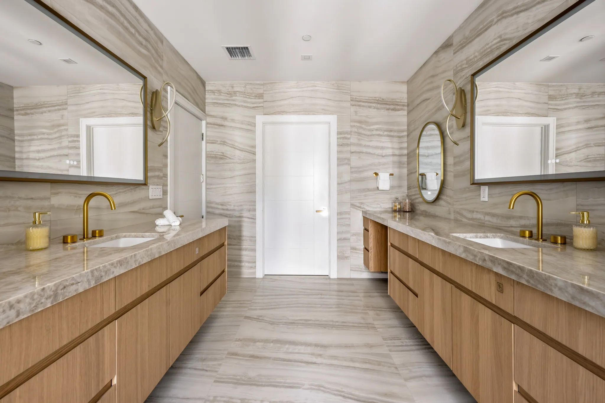 Primary bath with dual stone vanities and matching backlit mirrors