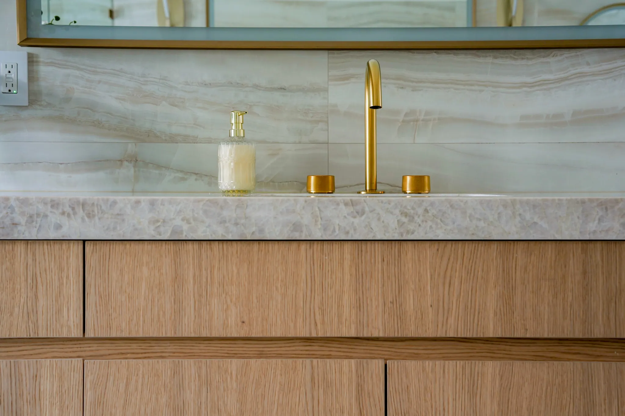 Detail of primary vanity with quartzite top and brass fixtures
