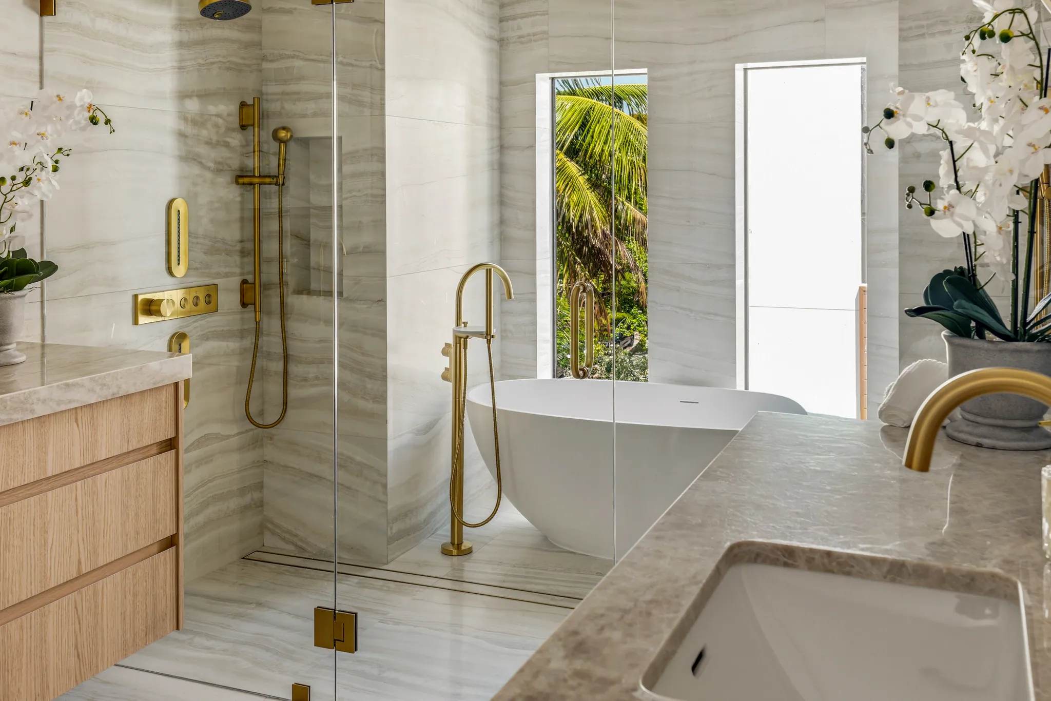 Primary bath with freestanding tub, glass shower and palm view