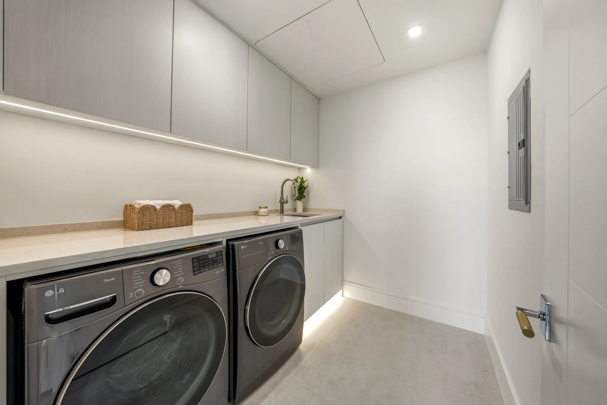 Laundry room with stacked LG washer dryer and quartzite counter sink